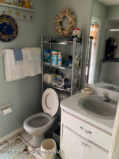 bathroom featuring toilet, baseboards, vanity, and tile patterned floors