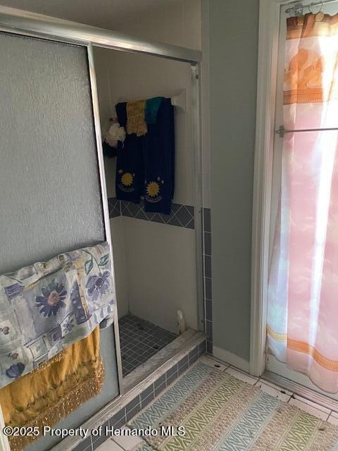 bathroom with a stall shower and tile patterned floors