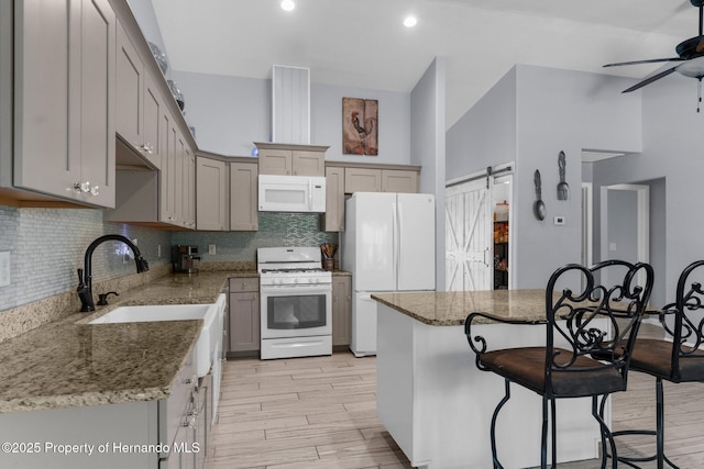 13415 Ester Dr, Brooksville, FL 34613 - kitchen featuring a ceiling fan, a breakfast bar, white appliances, light wood-type flooring, and backsplash