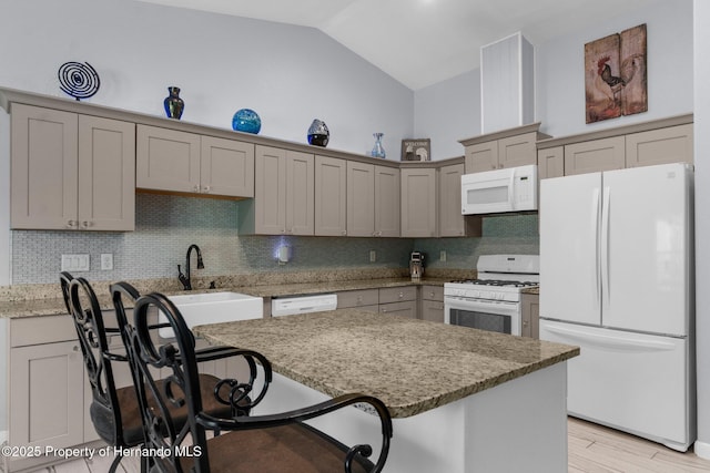 13415 Ester Dr, Brooksville, FL 34613 - kitchen featuring a sink, vaulted ceiling, white appliances, light stone counters, and a breakfast bar area