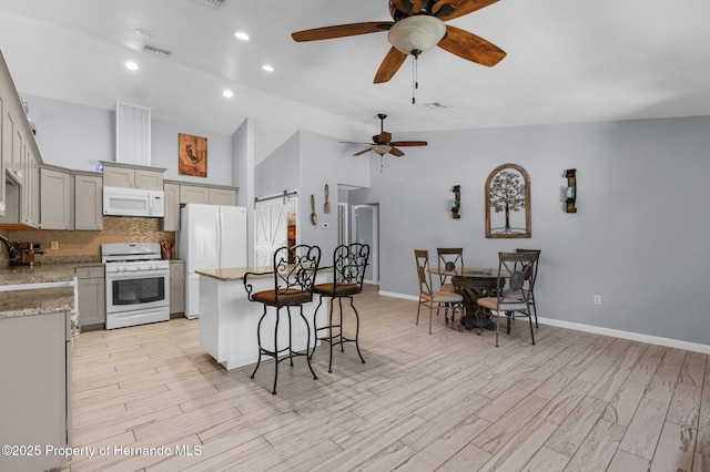 13415 Ester Dr, Brooksville, FL 34613 - kitchen with a center island, a ceiling fan, tasteful backsplash, a breakfast bar, and white appliances