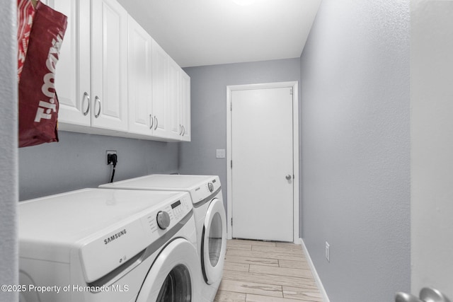 13415 Ester Dr, Brooksville, FL 34613 - laundry area with baseboards, washer and clothes dryer, light wood-style floors, and cabinet space