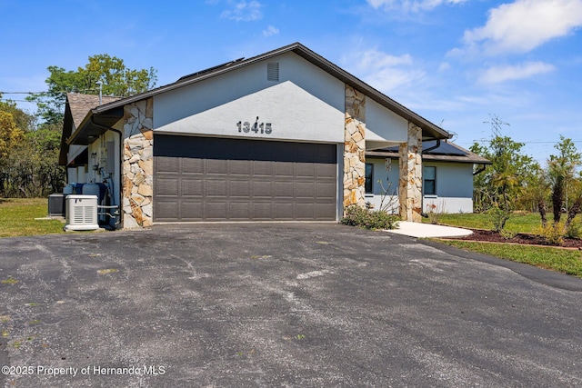 13415 Ester Dr, Brooksville, FL 34613 - ranch-style house featuring driveway, stone siding, cooling unit, a garage, and stucco siding