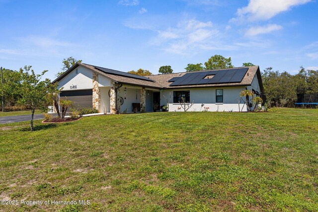 13415 Ester Dr, Brooksville, FL 34613 - single story home featuring a trampoline, an attached garage, roof mounted solar panels, a front yard, and stucco siding
