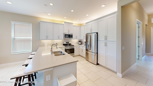 kitchen with a breakfast bar, stainless steel appliances, decorative backsplash, a sink, and a peninsula