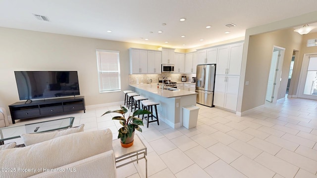 kitchen featuring open floor plan, appliances with stainless steel finishes, a breakfast bar area, and visible vents