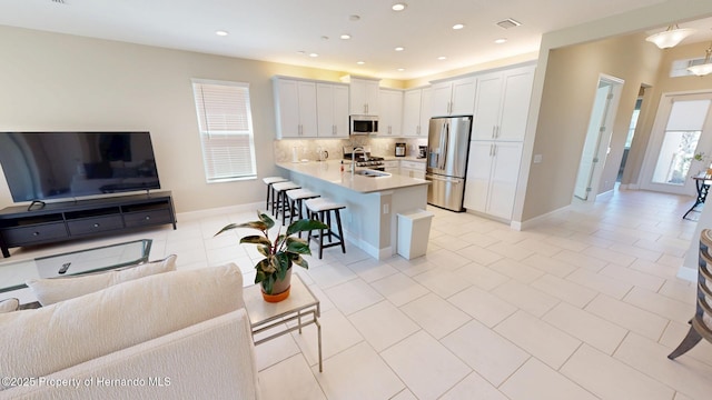 kitchen featuring appliances with stainless steel finishes, open floor plan, a breakfast bar area, and light countertops