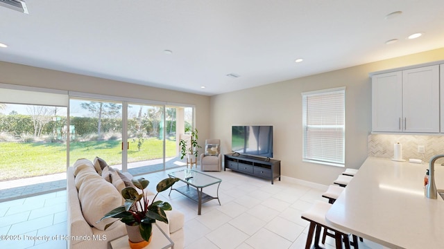 living area with light tile patterned floors, baseboards, visible vents, and recessed lighting