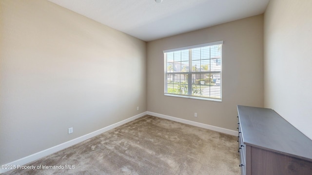 spare room with light carpet and baseboards