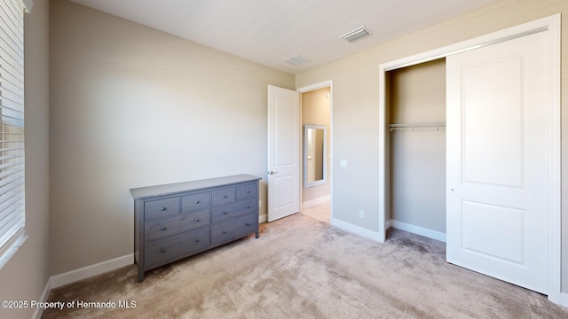 unfurnished bedroom with carpet, a closet, visible vents, and baseboards