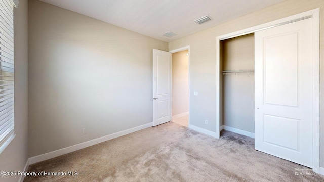 unfurnished bedroom featuring carpet floors, a closet, visible vents, and baseboards