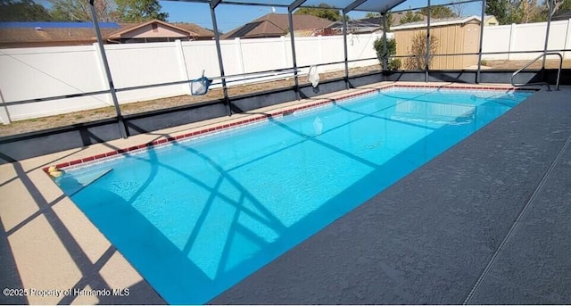 view of pool with glass enclosure, a fenced backyard, a fenced in pool, and a patio