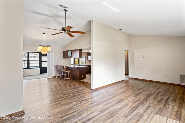 2013 Meredith Dr, Spring Hill, FL 34608 - living room featuring wood finished floors, ceiling fan, baseboards, high vaulted ceiling, and a chandelier