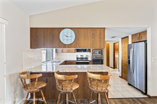 2013 Meredith Dr, Spring Hill, FL 34608 - kitchen with stainless steel appliances, a peninsula, brown cabinets, a sink, and lofted ceiling