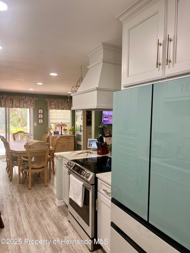 kitchen with electric stove, light wood-type flooring, fridge, premium range hood, and white cabinetry