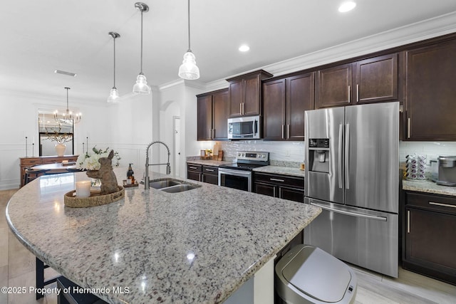 kitchen featuring a kitchen breakfast bar, ornamental molding, appliances with stainless steel finishes, and a sink