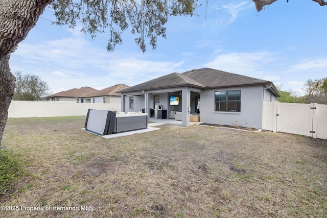 rear view of property featuring a patio area, a yard, a fenced backyard, and a gate