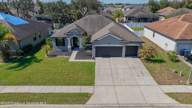 view of front of property with a front yard, an attached garage, a shingled roof, concrete driveway, and a residential view