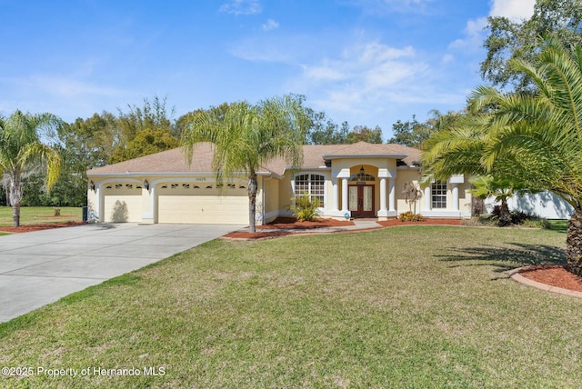 mediterranean / spanish-style house with a front yard, concrete driveway, an attached garage, and stucco siding