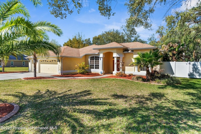 mediterranean / spanish-style house featuring a garage, fence, driveway, stucco siding, and a front lawn