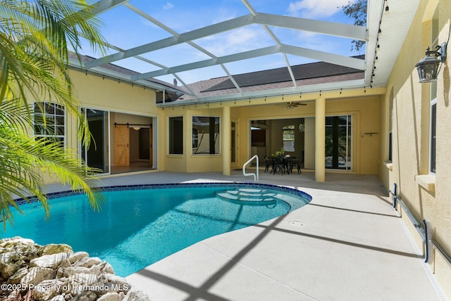 pool featuring glass enclosure, ceiling fan, and a patio