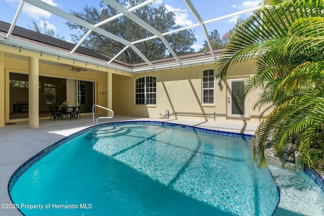 pool featuring glass enclosure, a patio area, and ceiling fan