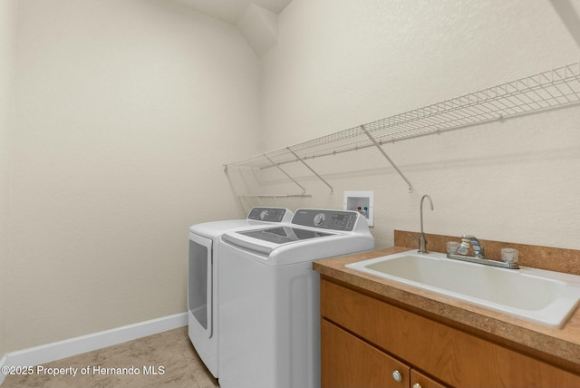 clothes washing area with washer and clothes dryer, cabinet space, light tile patterned flooring, a sink, and baseboards