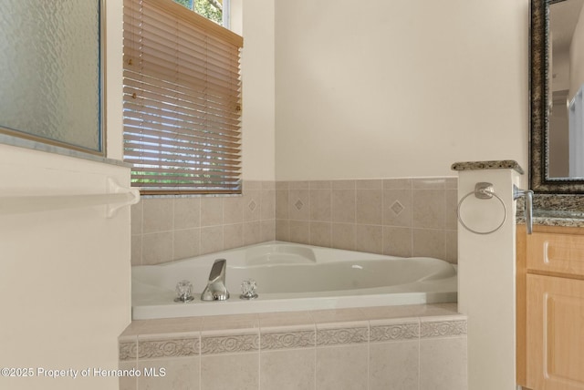 bathroom featuring a garden tub, plenty of natural light, and vanity