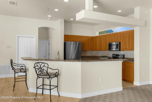 kitchen featuring visible vents, stainless steel appliances, and dark stone counters