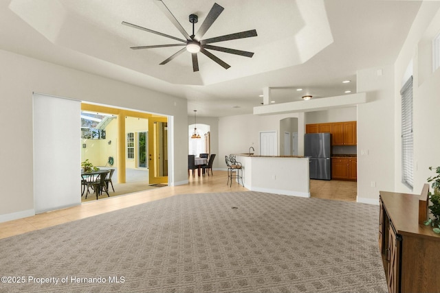 living area with light tile patterned floors, baseboards, a tray ceiling, and light colored carpet