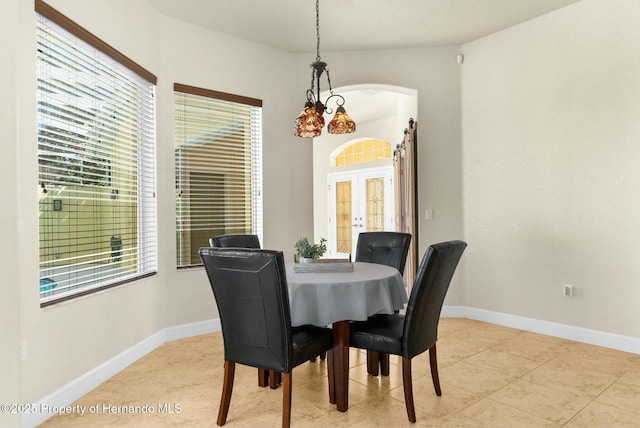 dining area with light tile patterned floors, baseboards, arched walkways, and french doors