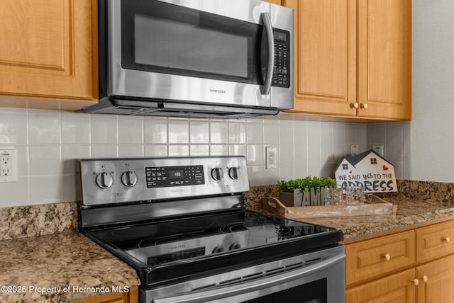 kitchen featuring appliances with stainless steel finishes, backsplash, and light stone counters