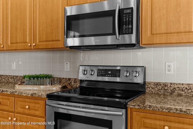 kitchen with brown cabinets, stone countertops, stainless steel appliances, and backsplash