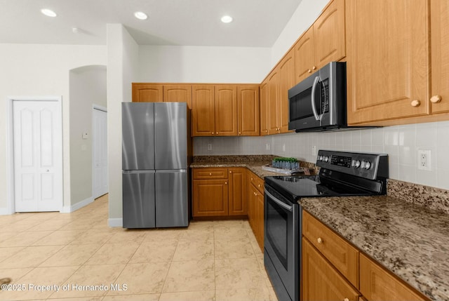 kitchen with tasteful backsplash, dark stone counters, stainless steel appliances, and recessed lighting