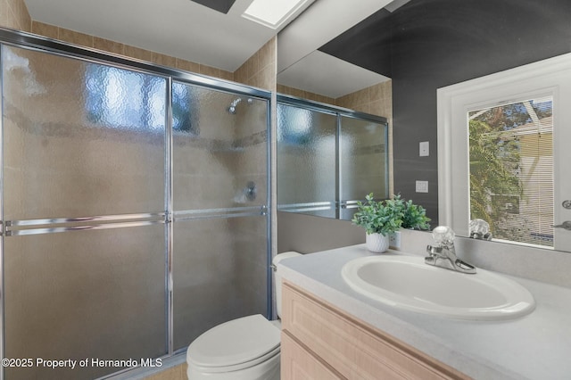 full bathroom with vanity, a shower stall, and toilet