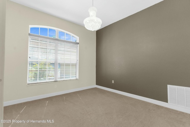 carpeted empty room with baseboards, a chandelier, visible vents, and a healthy amount of sunlight