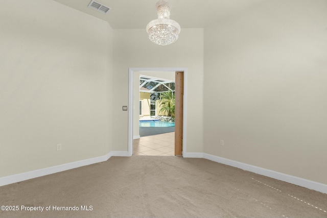 carpeted empty room featuring an inviting chandelier, visible vents, and baseboards