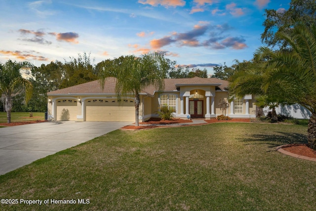 mediterranean / spanish-style house with a garage, french doors, concrete driveway, a yard, and stucco siding