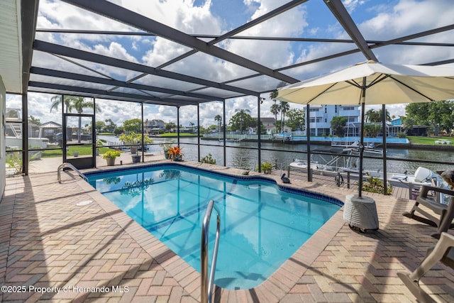 pool with glass enclosure, a patio area, and a water view