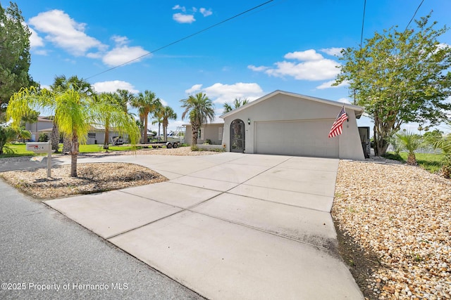 ranch-style house featuring a garage, concrete driveway, and stucco siding