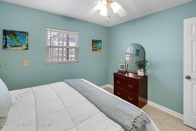 tiled bedroom featuring a ceiling fan and baseboards