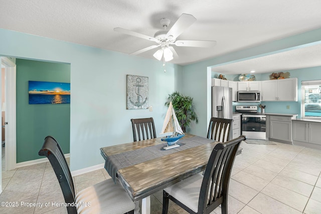 dining room with light tile patterned floors, a ceiling fan, baseboards, and a textured ceiling