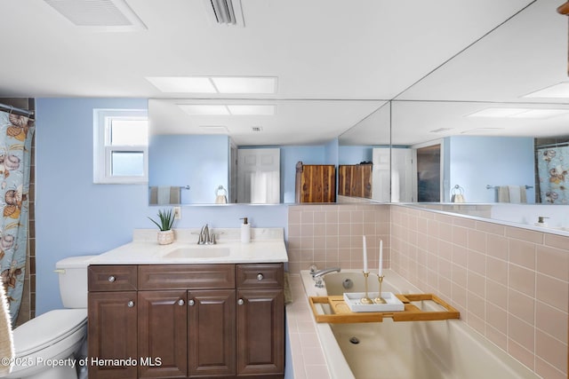 bathroom with toilet, a skylight, visible vents, vanity, and a bath