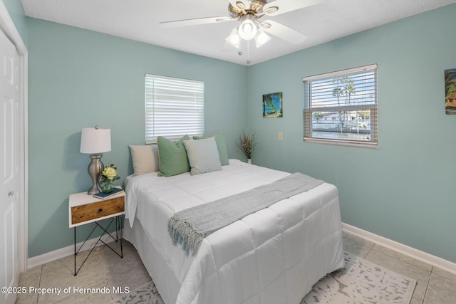 bedroom with ceiling fan, baseboards, and light tile patterned floors