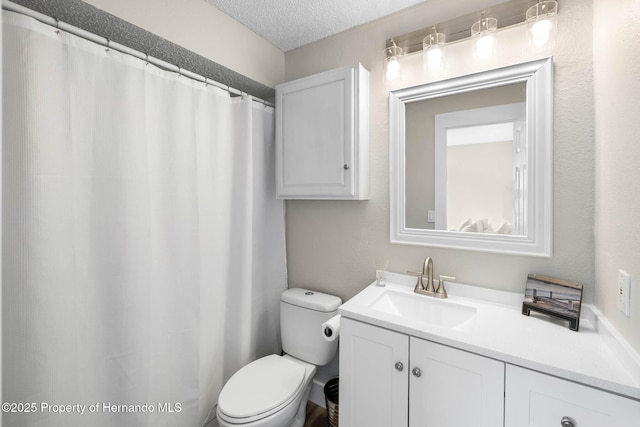 bathroom with a textured ceiling, vanity, and toilet