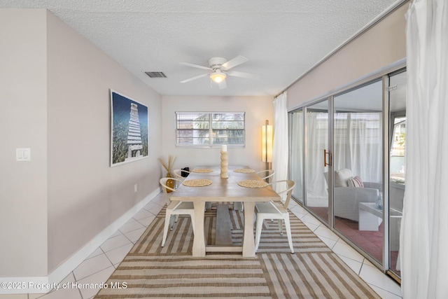 dining area with light tile patterned floors, visible vents, baseboards, ceiling fan, and a textured ceiling