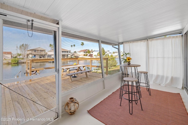 sunroom featuring a water view