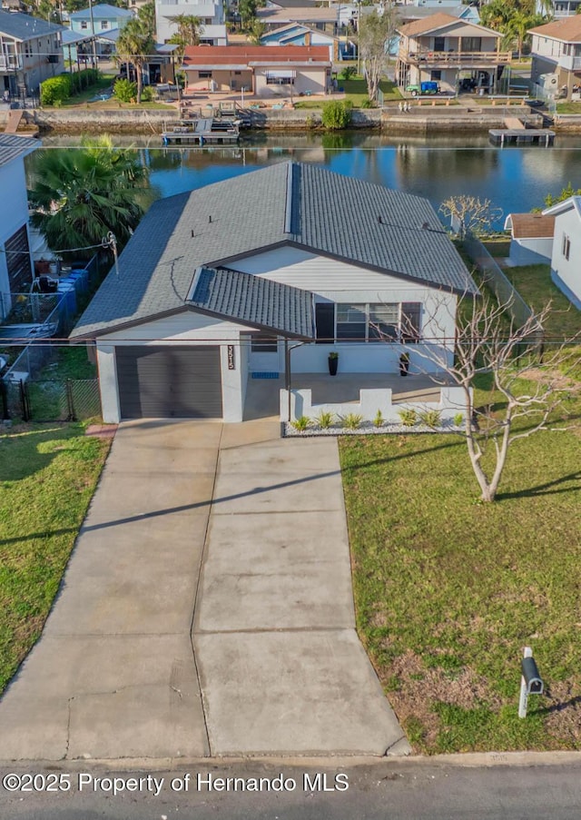 view of front facade featuring a garage, a residential view, a water view, a front yard, and stucco siding