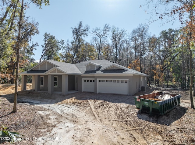 view of front of house featuring a garage, central AC, a shingled roof, and stucco siding