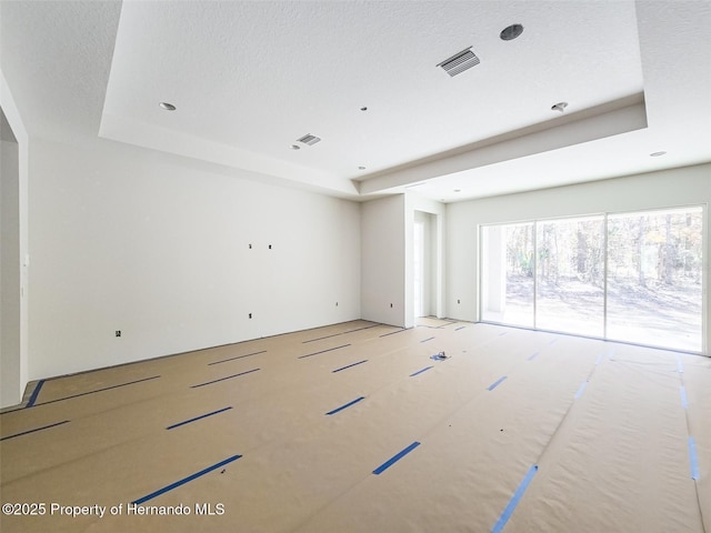 empty room featuring a textured ceiling, a raised ceiling, and visible vents